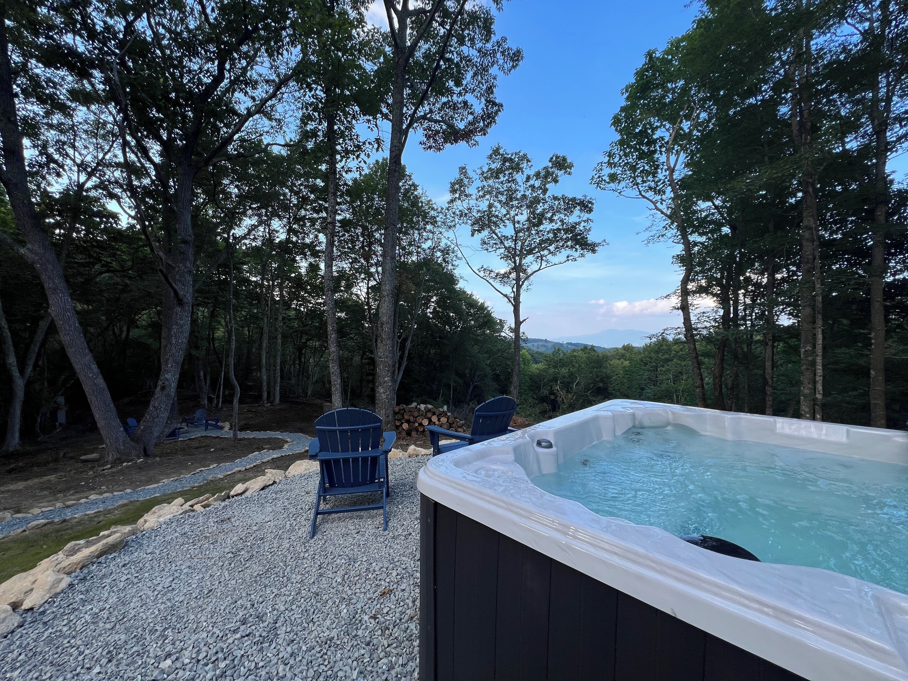 A hot tub surrounded by trees, with a view of distant hills.