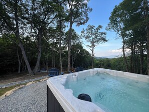 A hot tub surrounded by trees with a clear sky in the background. - Hidden Creek Cabin at Monteagle (Banner Elk)