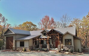 A two-story house with a stone foundation, a metal roof, and a wooden porch. - Hidden Creek Cabin at Monteagle (Banner Elk)