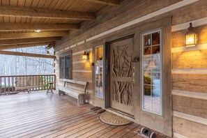 A wooden cabin with a porch, a bench, and a door with a tree design. - Journeys End at Valle Crucis (Banner Elk)