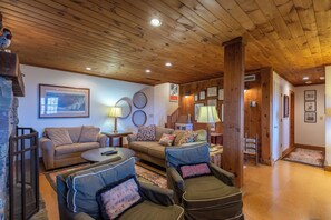 A cozy living room with wooden ceilings, a brown sofa, two armchairs, and a coffee table. - Journeys End at Valle Crucis (Banner Elk)