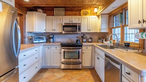 A kitchen with white cabinets, stainless steel appliances, and a wooden ceiling. - Journeys End at Valle Crucis (Banner Elk)
