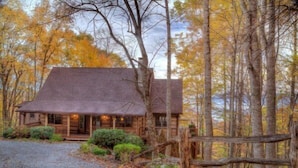 A rustic cabin with a porch, surrounded by a forest with autumn foliage. - Journeys End at Valle Crucis (Banner Elk)