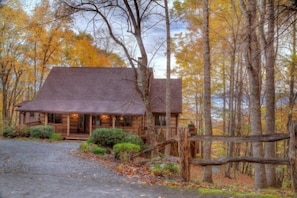 A rustic cabin with a porch, surrounded by a forest with autumn foliage. - Journeys End at Valle Crucis (Banner Elk)