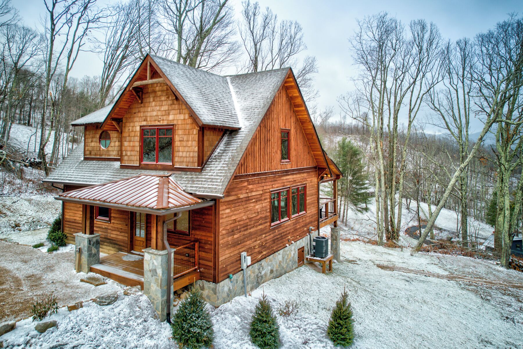 Une cabane en bois avec des fondations en pierre, une véranda et une cheminée.