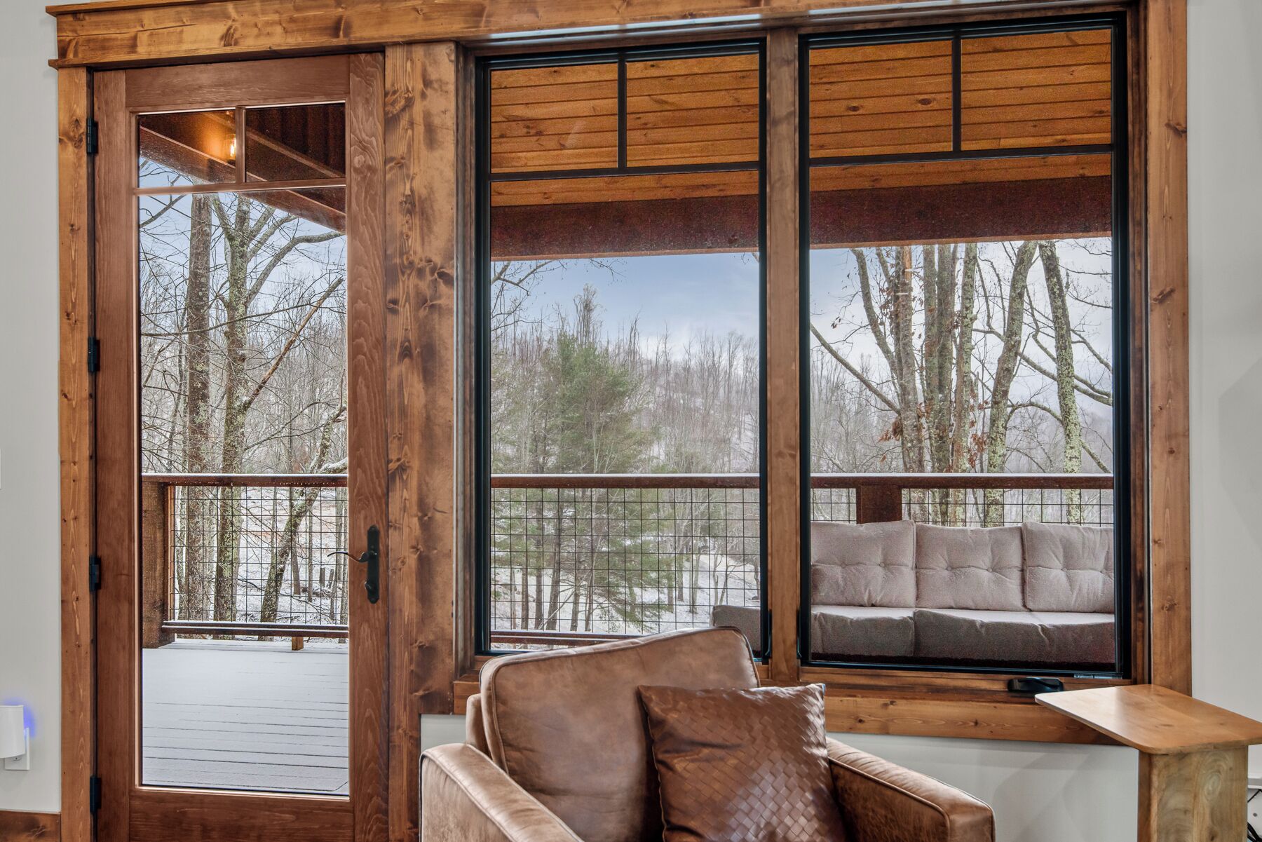 A wooden-framed window with a view of a deck and trees.