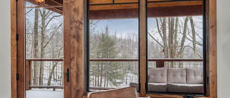 A wooden-framed window with a view of a deck and trees.