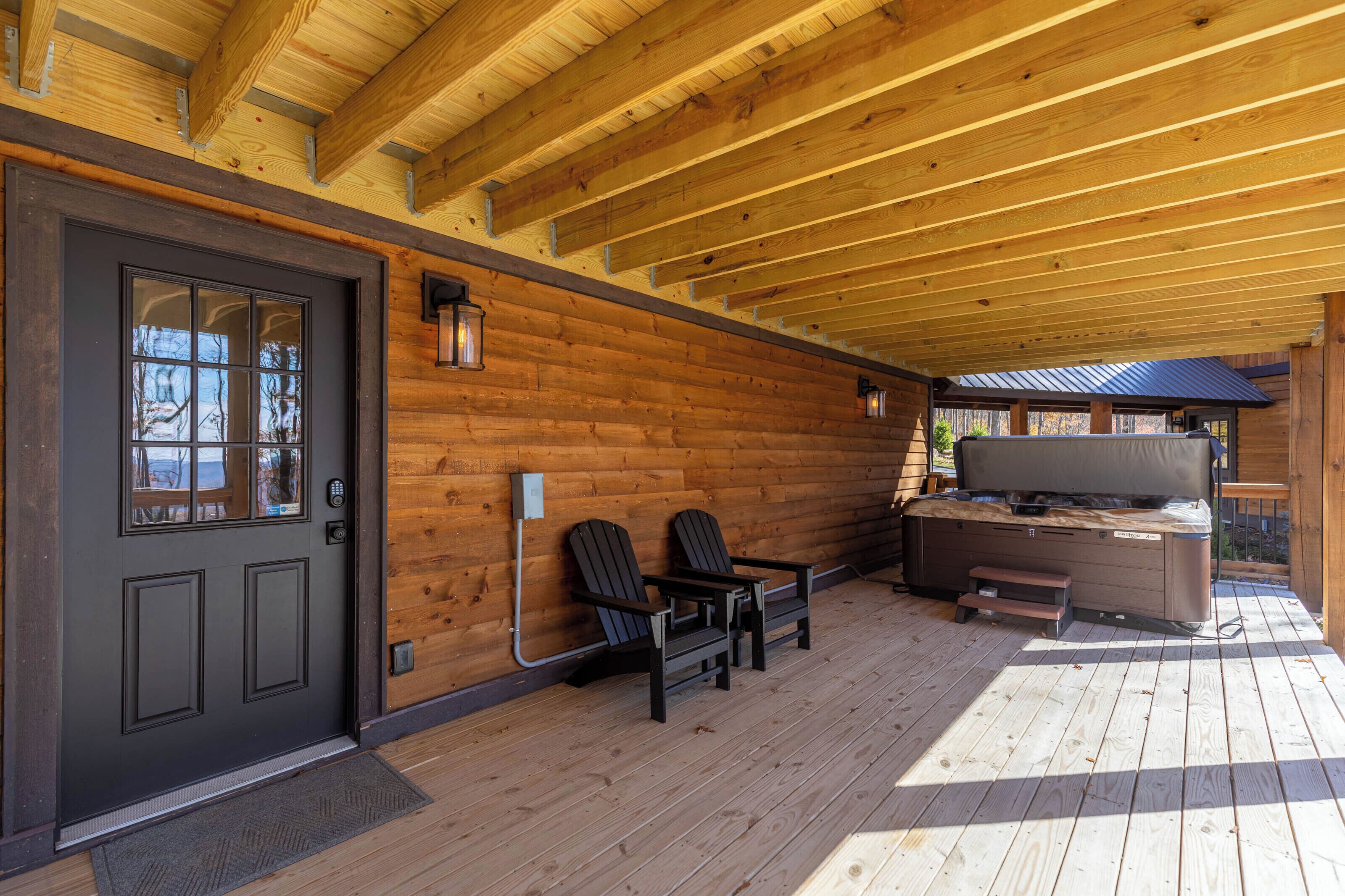 A wooden deck with a door, two Adirondack chairs, and a barbecue grill.