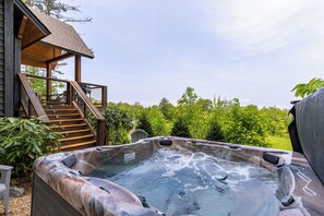A hot tub with a wooden deck and stairs leading to a covered area. - Just Bluffin' at Eagles Nest (Banner Elk)