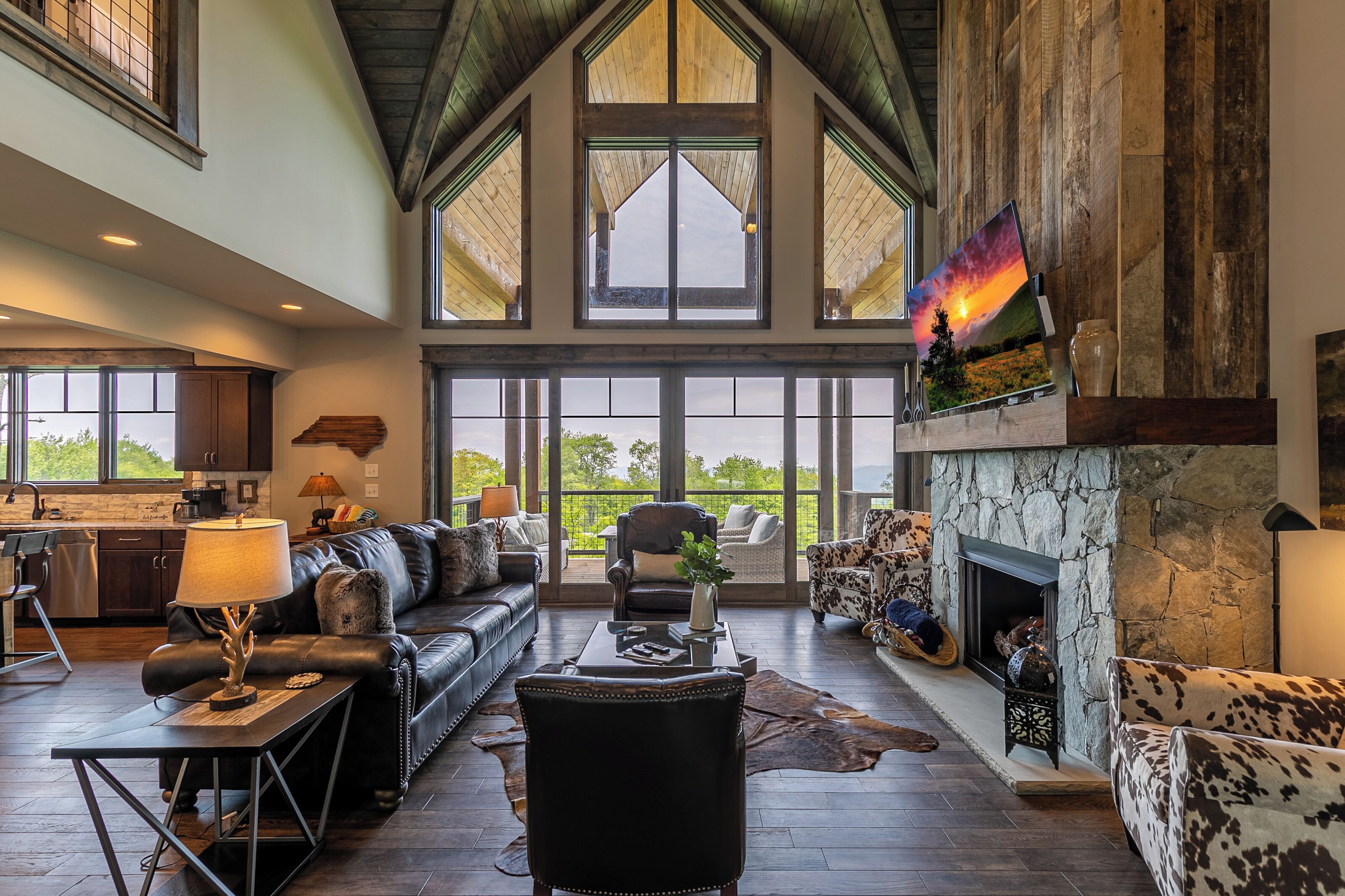 A spacious living area with a fireplace, leather furniture, and large windows offering a view of the outdoors.