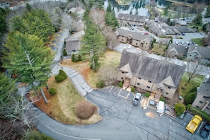 An aerial view of a residential area with houses, a parking lot, and a large building with multiple stories.