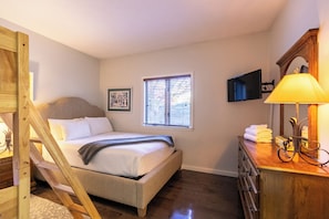 A bedroom with a bed, a window with blinds, a bedside table with a lamp, and a dresser. - Chetola Robin 1 (Blowing Rock)