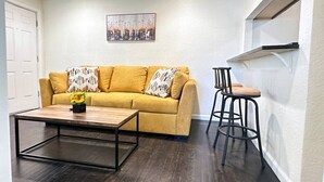 Una sala de estar con un sofá, una mesa de centro y un taburete de bar.