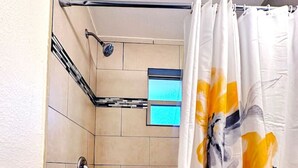 Un baño con bañera, cortina de ducha y paredes de cerámica.