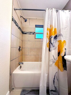 Ein Badezimmer mit Badewanne, Duschvorhang und gefliesten Wänden.