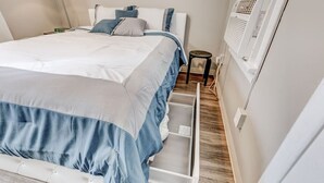 Ein ordentlich bezogenes Bett mit ausziehbarer Schlaffläche, ein Nachttisch und eine Wand-Klimaanlage.
