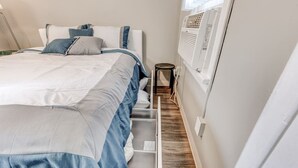 Ein Schlafzimmer mit einem Bett, einem Nachttisch und einer Wand-Klimaanlage.