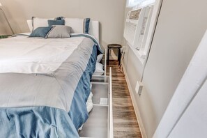 Ein Schlafzimmer mit einem Bett, einem Nachttisch und einer Wand-Klimaanlage.