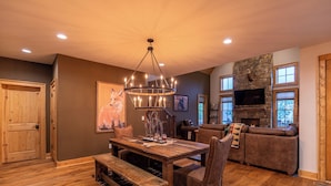 A cozy living room with a stone fireplace, wooden furniture, and a large TV. - Bearingers Bluff at Eagles Nest (Banner Elk)