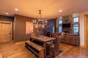 A cozy living room with a stone fireplace, wooden furniture, and a large TV. - Bearingers Bluff at Eagles Nest (Banner Elk)