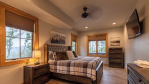 A bedroom with a large bed, wooden headboard, and a window with blinds. - Bearingers Bluff at Eagles Nest (Banner Elk)