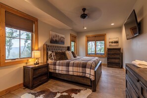 A bedroom with a large bed, wooden headboard, and a window with blinds. - Bearingers Bluff at Eagles Nest (Banner Elk)