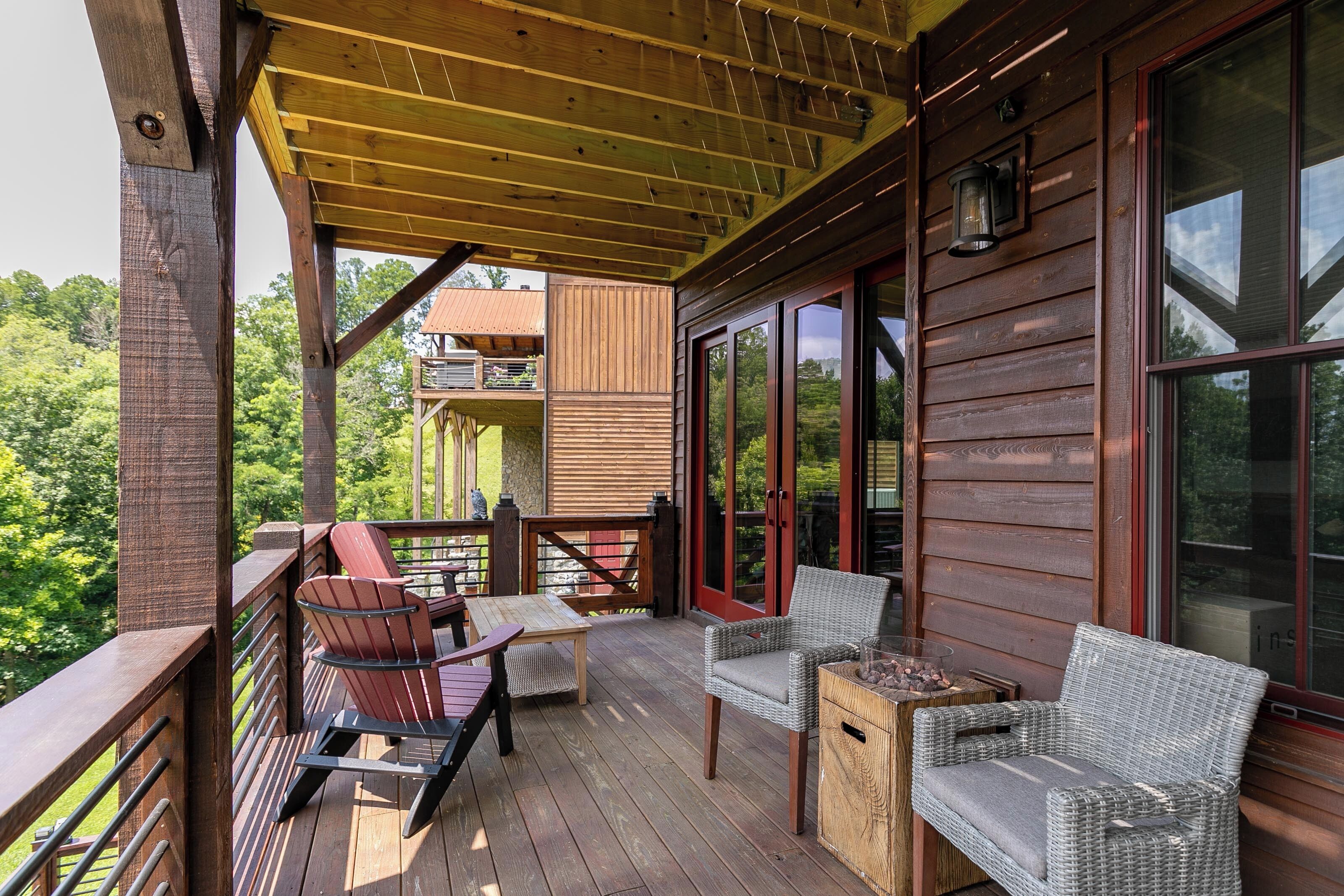 Eine Holzterrasse mit Korbmöbeln und einem Tisch, mit Blick auf eine üppige grüne Landschaft.