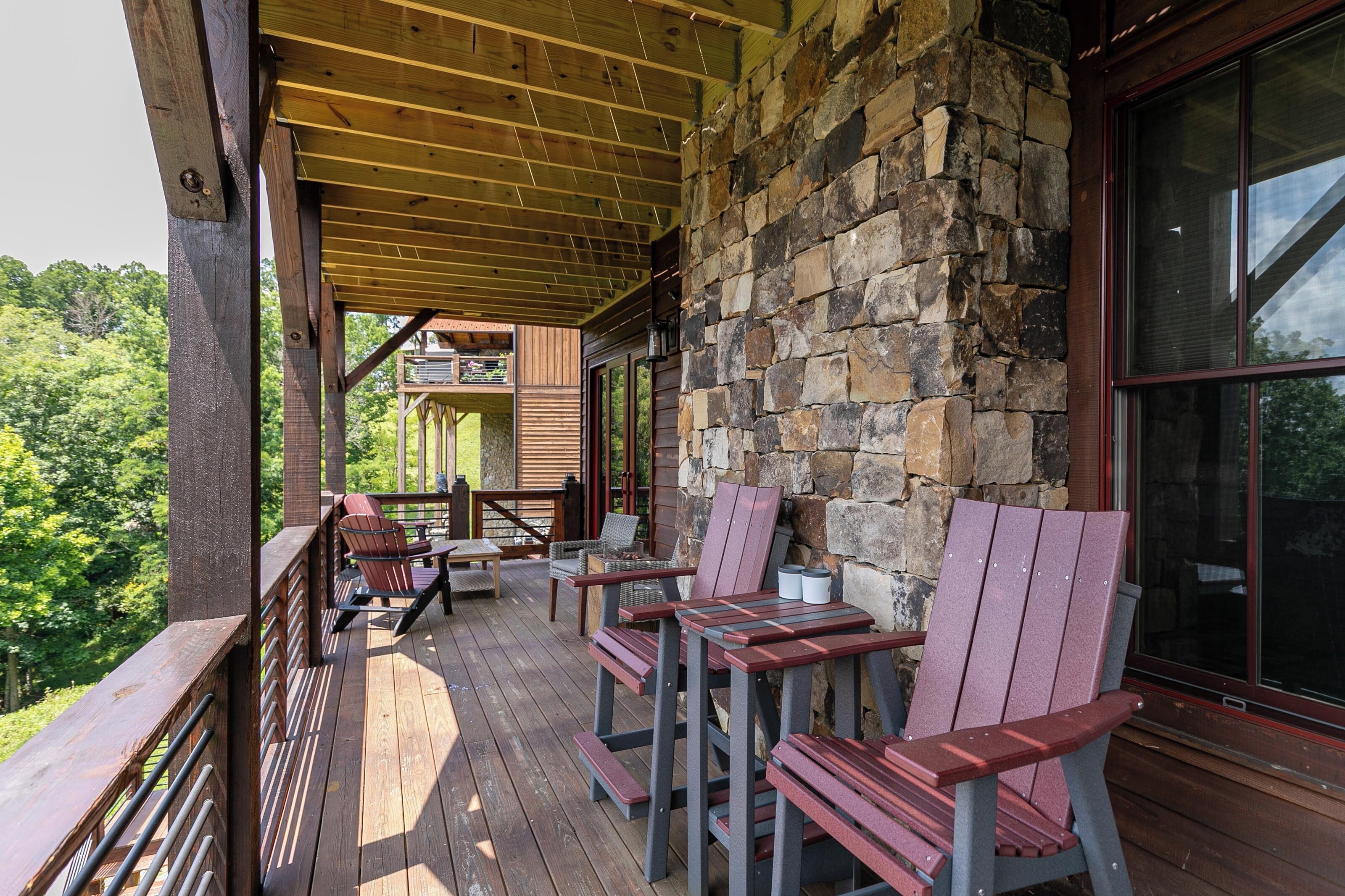 A wooden deck with Adirondack chairs and a stone wall.