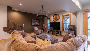 A spacious living room with a large sectional sofa, a wooden coffee table, a TV, and a fireplace. - Bearingers Bluff at Eagles Nest (Banner Elk)