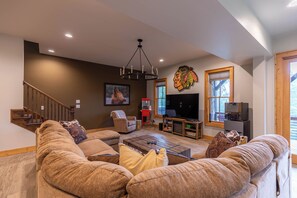 A spacious living room with a large sectional sofa, a wooden coffee table, a TV, and a fireplace. - Bearingers Bluff at Eagles Nest (Banner Elk)