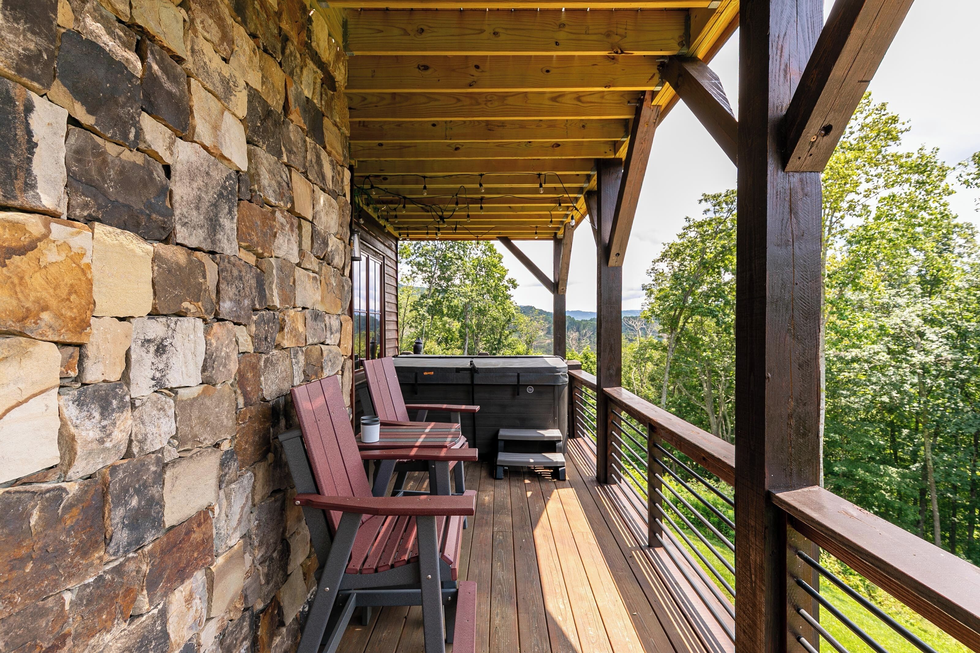 A covered outdoor area with stone walls, wooden deck, and a grill.
