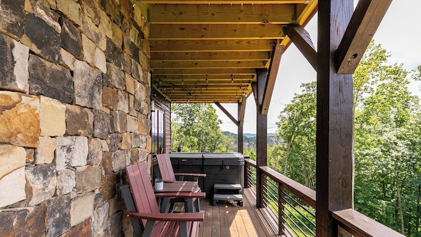 A covered outdoor area with stone walls, wooden deck, and a grill. - Bearingers Bluff at Eagles Nest (Banner Elk)