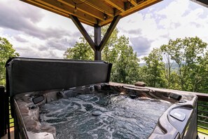Un bain à remous avec une terrasse en bois et une vue sur les arbres et les montagnes.