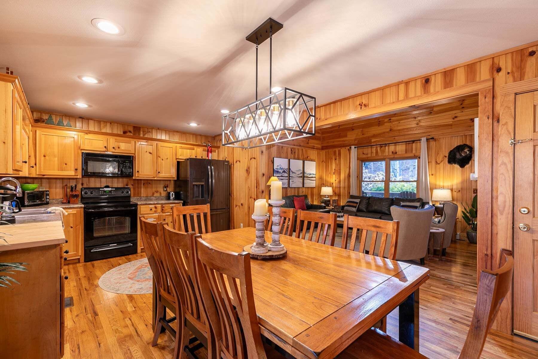 A wooden cabin interior with a kitchen, dining area, and living room.