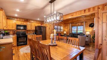 A wooden cabin interior with a kitchen, dining area, and living room.