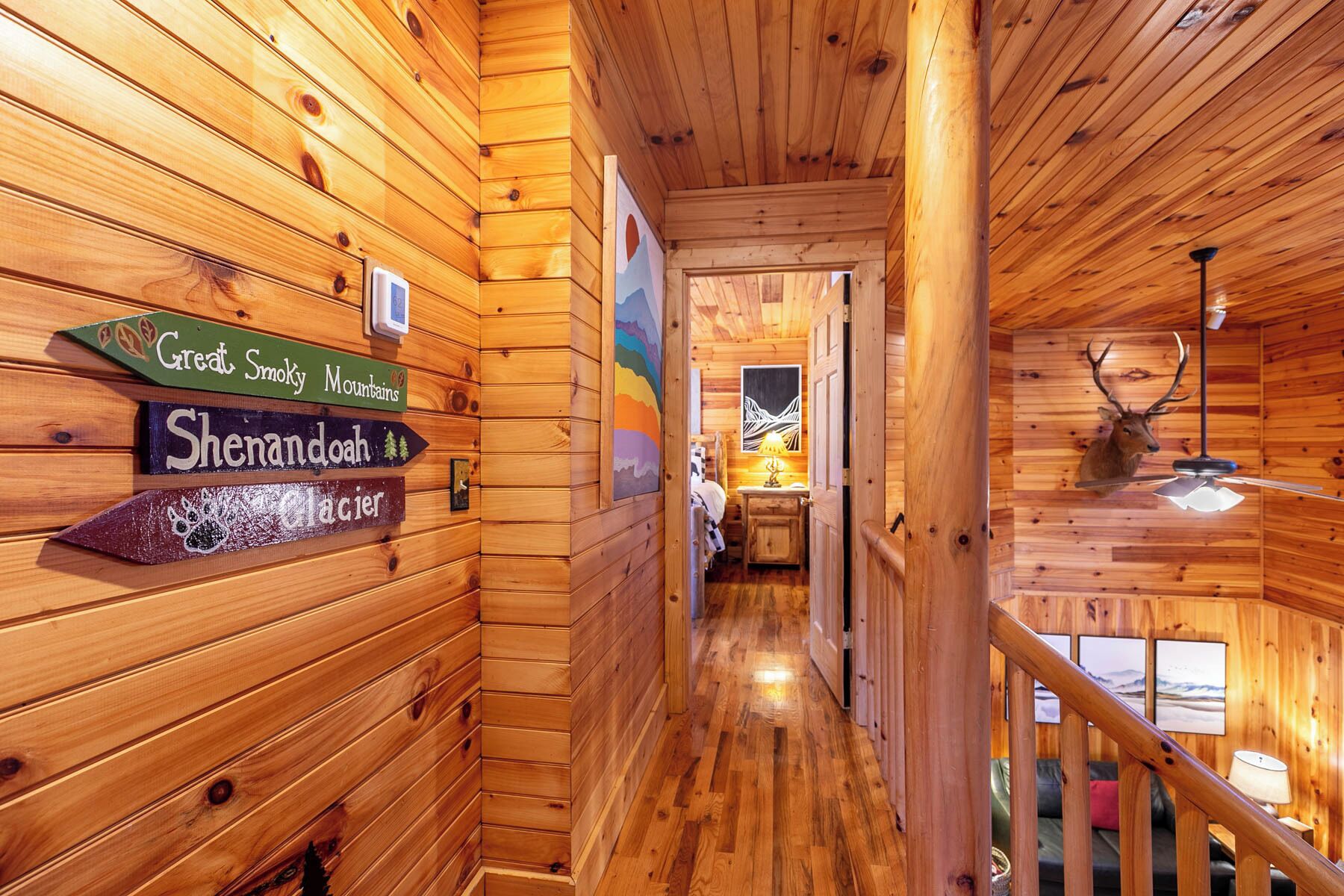 A wooden cabin interior with a hallway leading to a bedroom. There are signs indicating 'Great Smoky Mountains' and 'Shenandoah Glacier'.