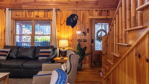A wooden interior with a leather sofa, a lamp, and a staircase. - Riverbend Retreat (Todd)