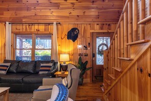 A wooden interior with a leather sofa, a lamp, and a staircase. - Riverbend Retreat (Todd)