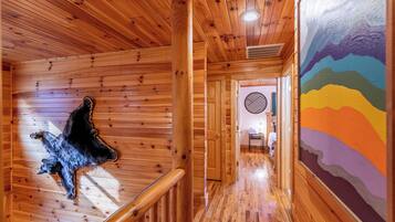 A wooden interior with a bear sculpture, a colorful mural, and a hallway leading to a room with a circular patterned wall.