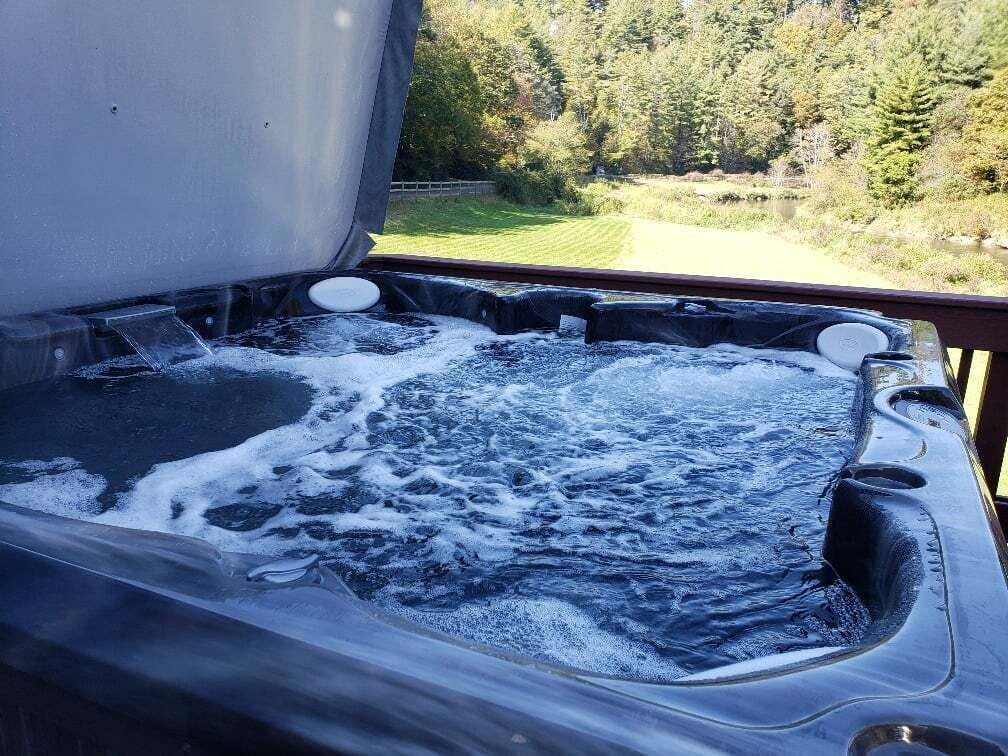 A hot tub with a view of a forested landscape.