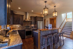 A modern kitchen with dark wood cabinets, stainless steel appliances, and a central island with bar stools.