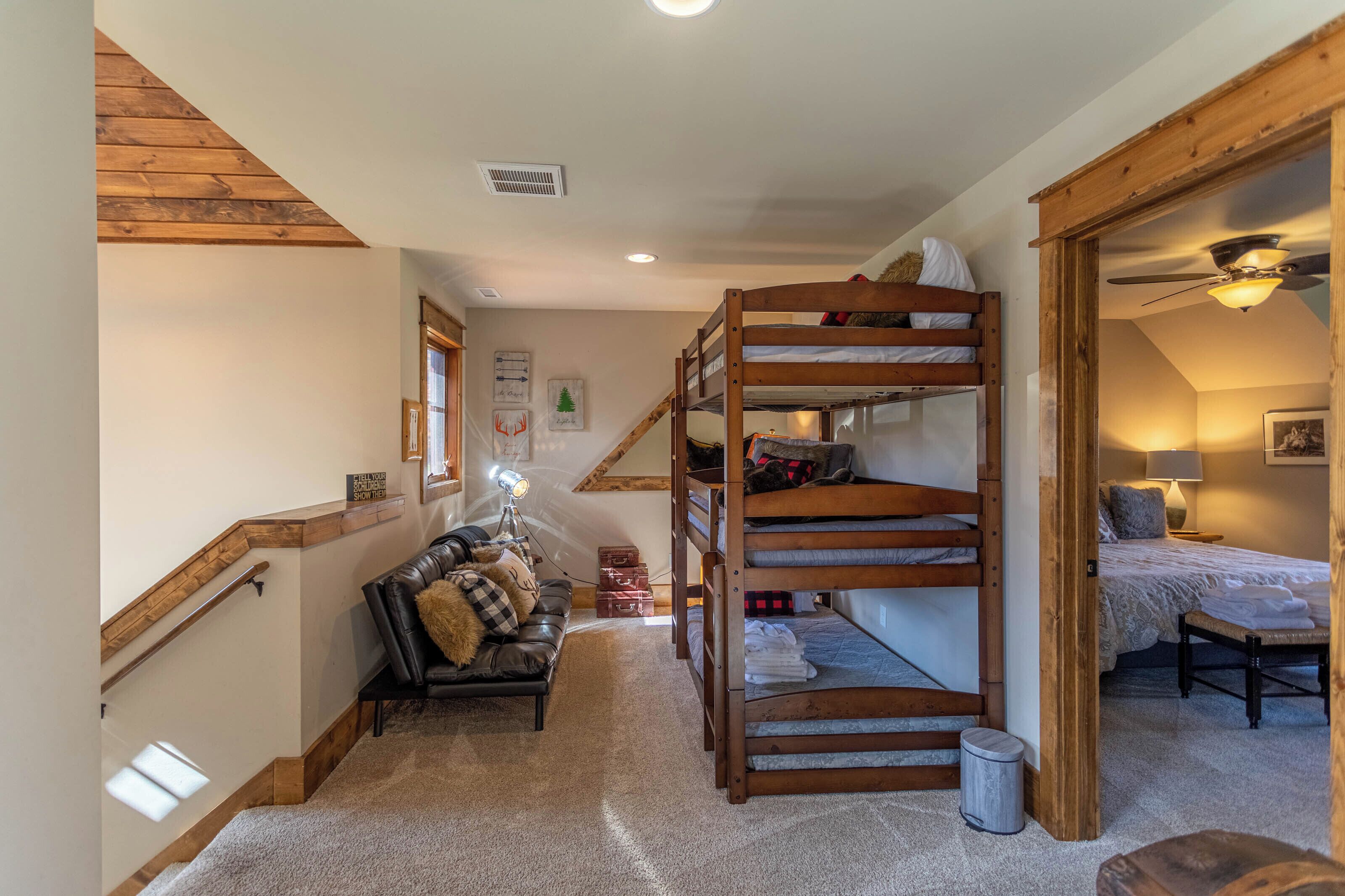 Ein gemütliches Zimmer mit einem Etagenbett, einer Schlafcouch und einer Treppe.