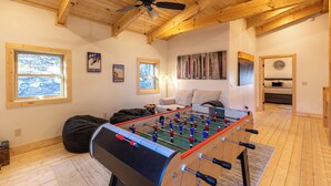 Een gezellige kamer met een tafelvoetbaltafel, houten balken en grote ramen.