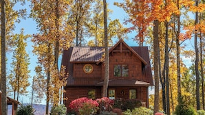 Eine Hütte, umgeben von hohen Bäumen im Herbstlaub.