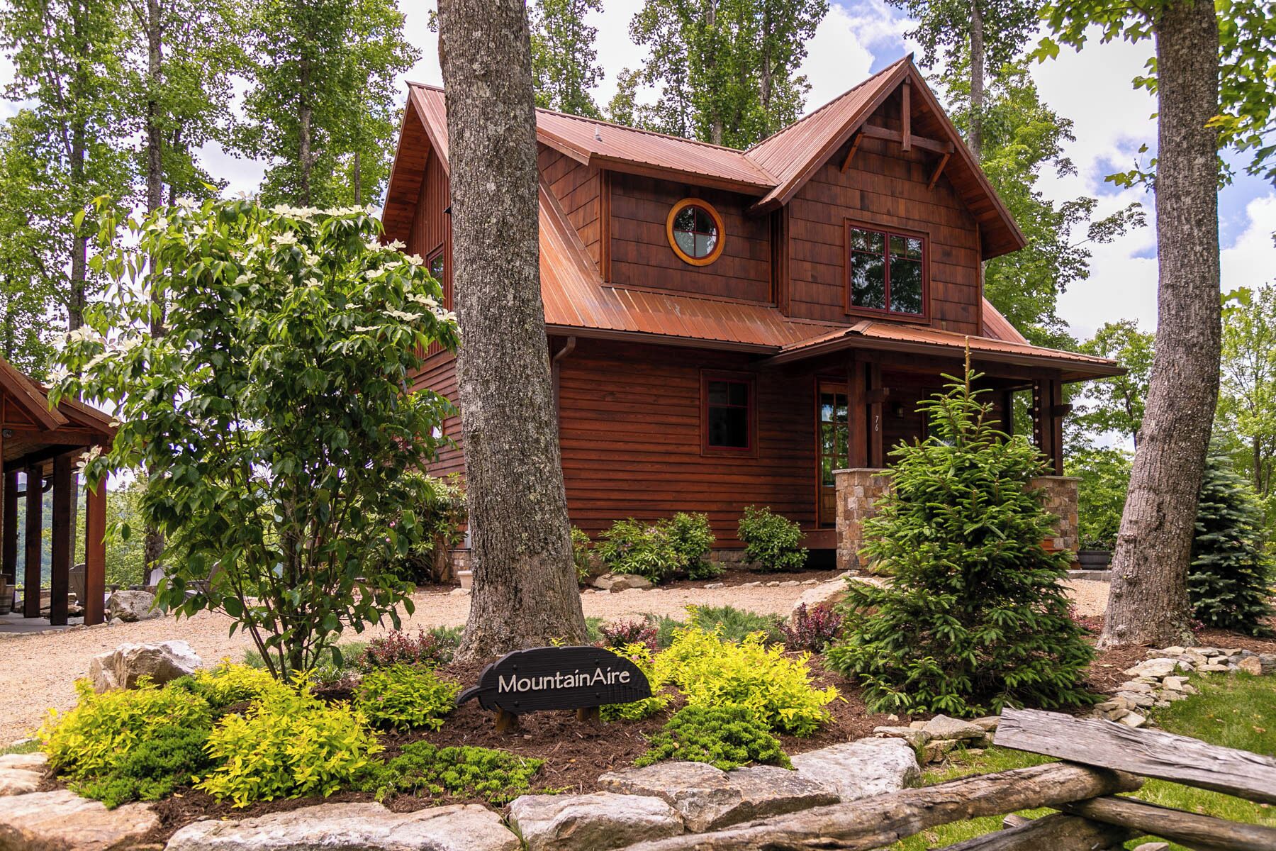 Une cabane en bois avec un porche, entourée d’arbres et sur laquelle on peut lire l’inscription « Mountain Aire ».