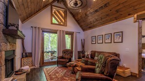 A cozy living room with a fireplace, leather furniture, and framed pictures on the wall. - Winterfell Lodge at Eagles Nest (Banner Elk)