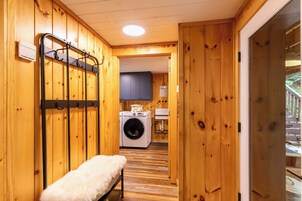 A wooden interior with a washing machine, a bench, and a rack.