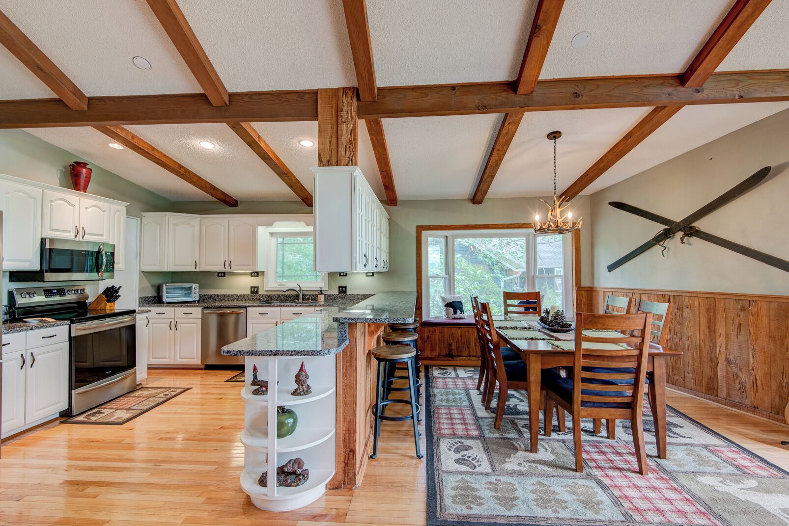 A spacious kitchen with wooden beams, white cabinets, and a large island with seating.
