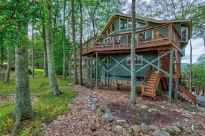 Eine Holzhütte mit Balkon und Treppe, umgeben von Bäumen.