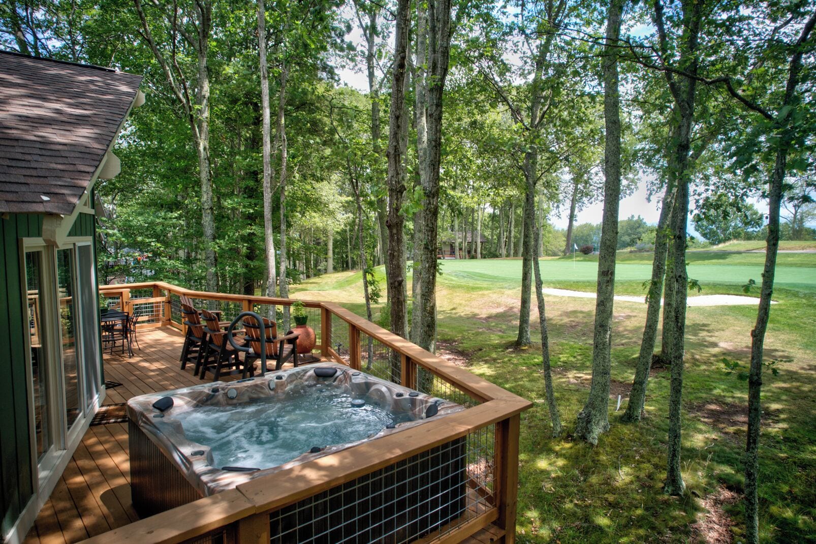 A hot tub on a wooden deck with a view of a golf course.